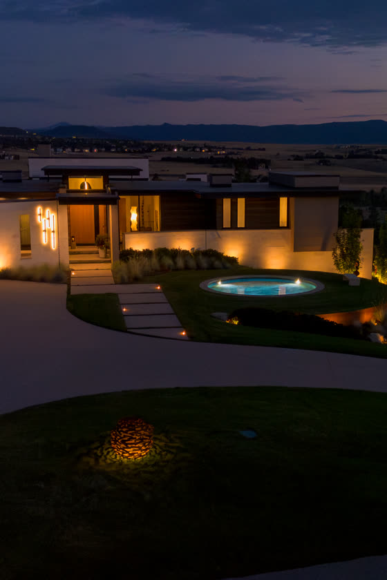 Aerial view of a modern Colorado home and pool lit at dusk