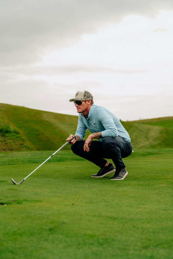 Golfer crouching to read a putt on the green