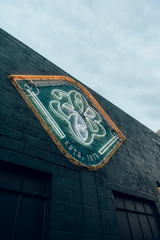 Neon brewery sign glowing on a brick exterior at night