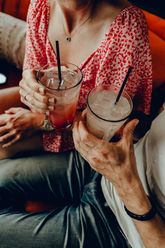 Two iced drinks held between friends at a table