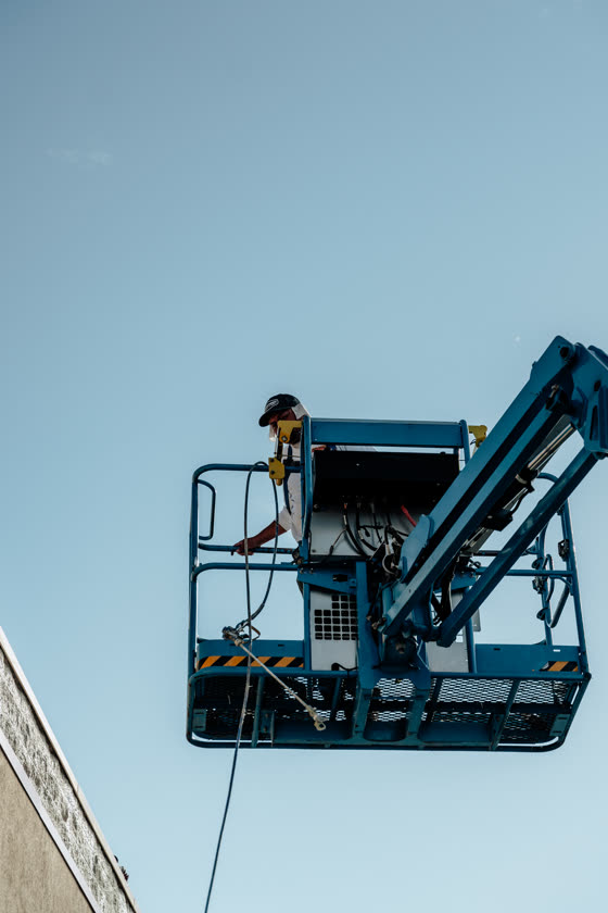 Worker running a boom lift high against an open sky